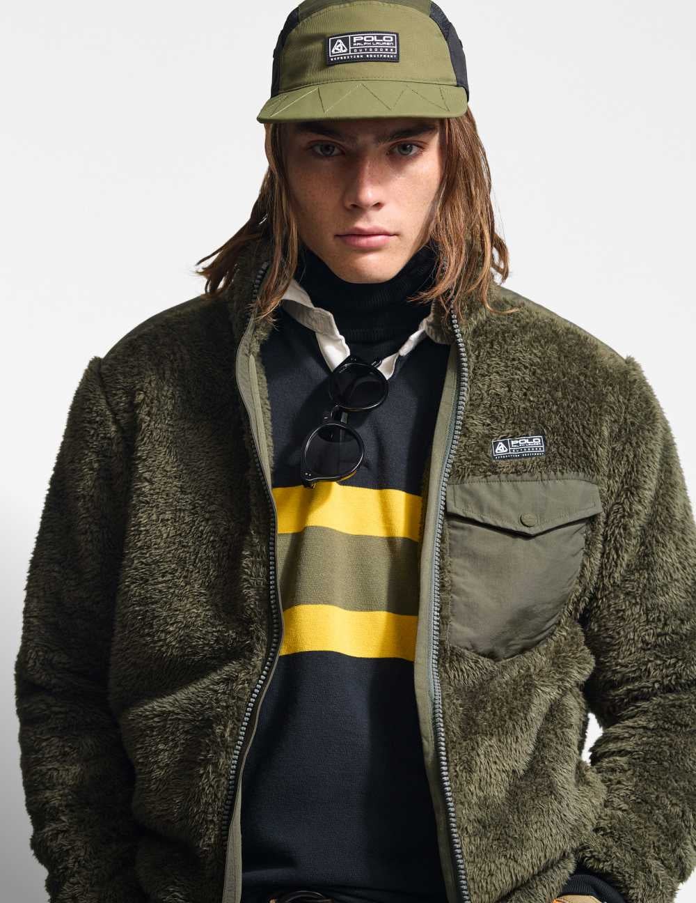 Man wears green fleece jacket over navy rugby shirt.