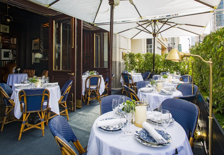 Patio with blue wicker chairs & tables with white tablecloths