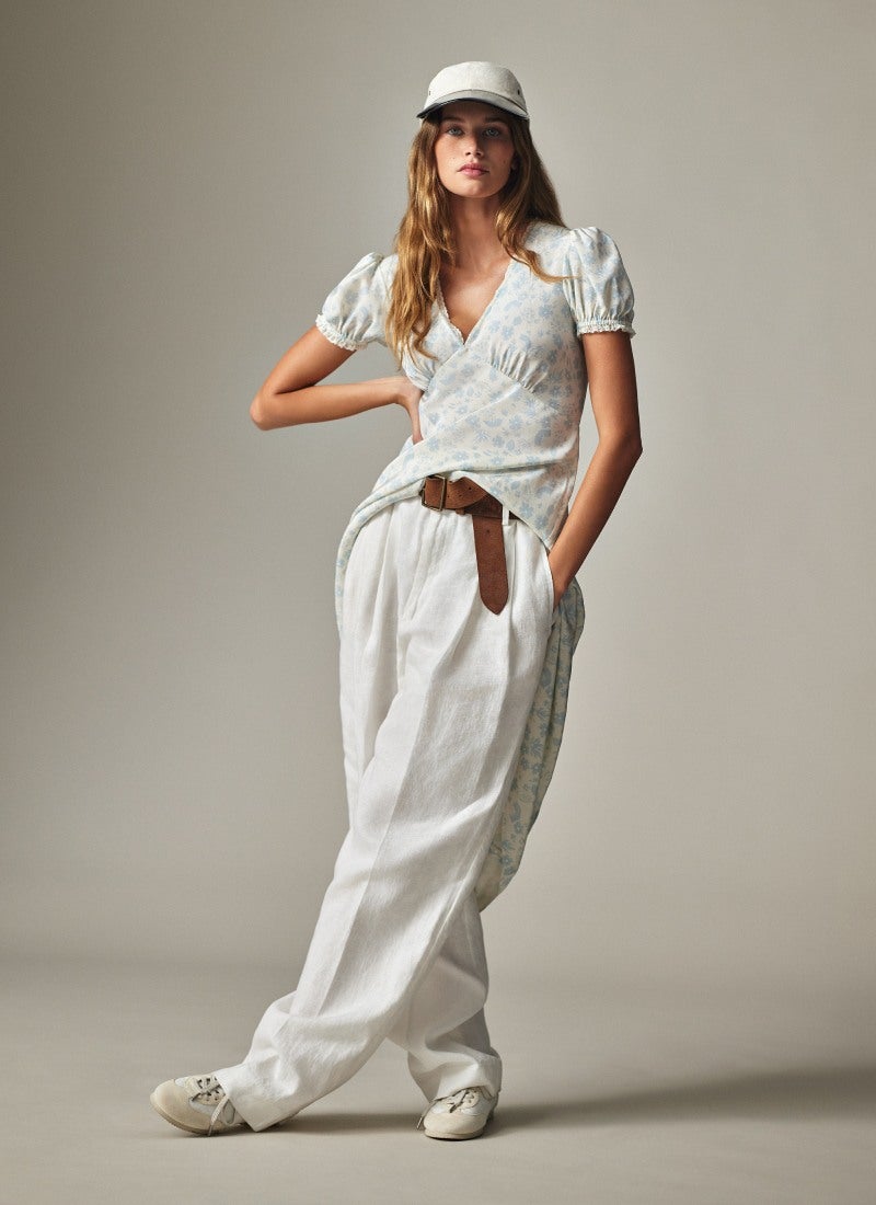 Woman wears white button-down and white frayed shorts.